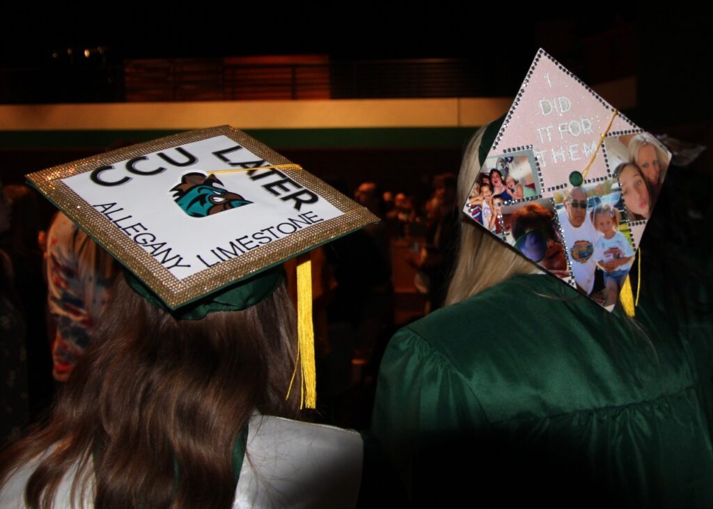 (Rick Miller/Olean Star) Two Allegany-Limestone graduates display messages on their mortar boards at graduation Saturday.