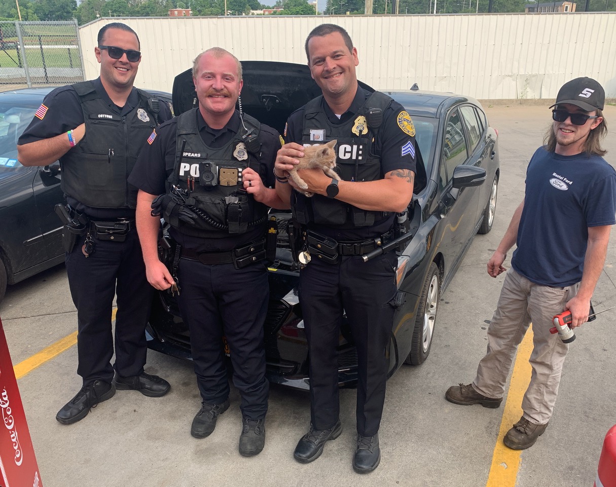 (Photo provided) It was a happy ending for a kitten stuck under a car hood Monday. From left are: Patrolmen Zack Spears and Joe Cottone; Sgt. Chris Lickfeld (holding the kitten) and Cordell Hill, an auto mechanic who helped remove panels so Lickfeld could grab it.