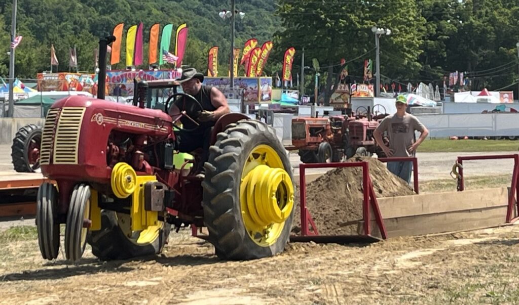 (Rick MIller/Olean Star The front end of this tractor in the Antique Tractor Pull rises under the strain of the load Saturday at the Cattaraugus County Fair.