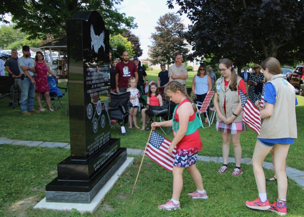 (Rick Miller/Olean Star)  Girl Scouts place American flags in from of the New Hinsdale Vietnam Memorial in Town Park during dedication ceremonies Saturday.