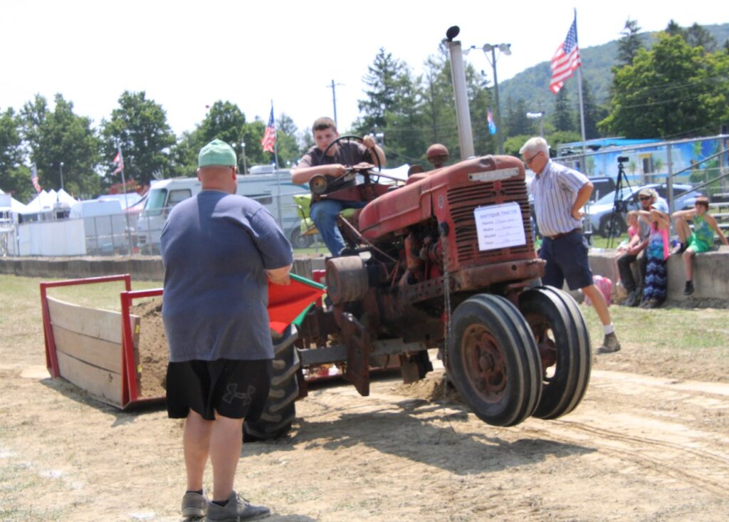 (Rick Miller/Oleam Star) The front wheels on this tractor in the Antique Tractor Pull rise from the ground as it strains under the load of the sand sled.