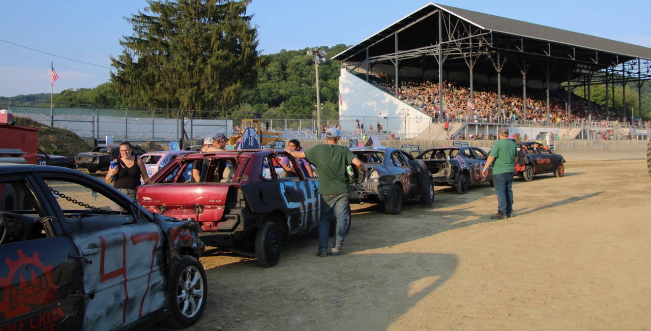 (Rick Miller/Olean Star) Demolition derby cars and their drivers lined up on the track near the grandstand at the Cattaraugus County Fair Monday night.
