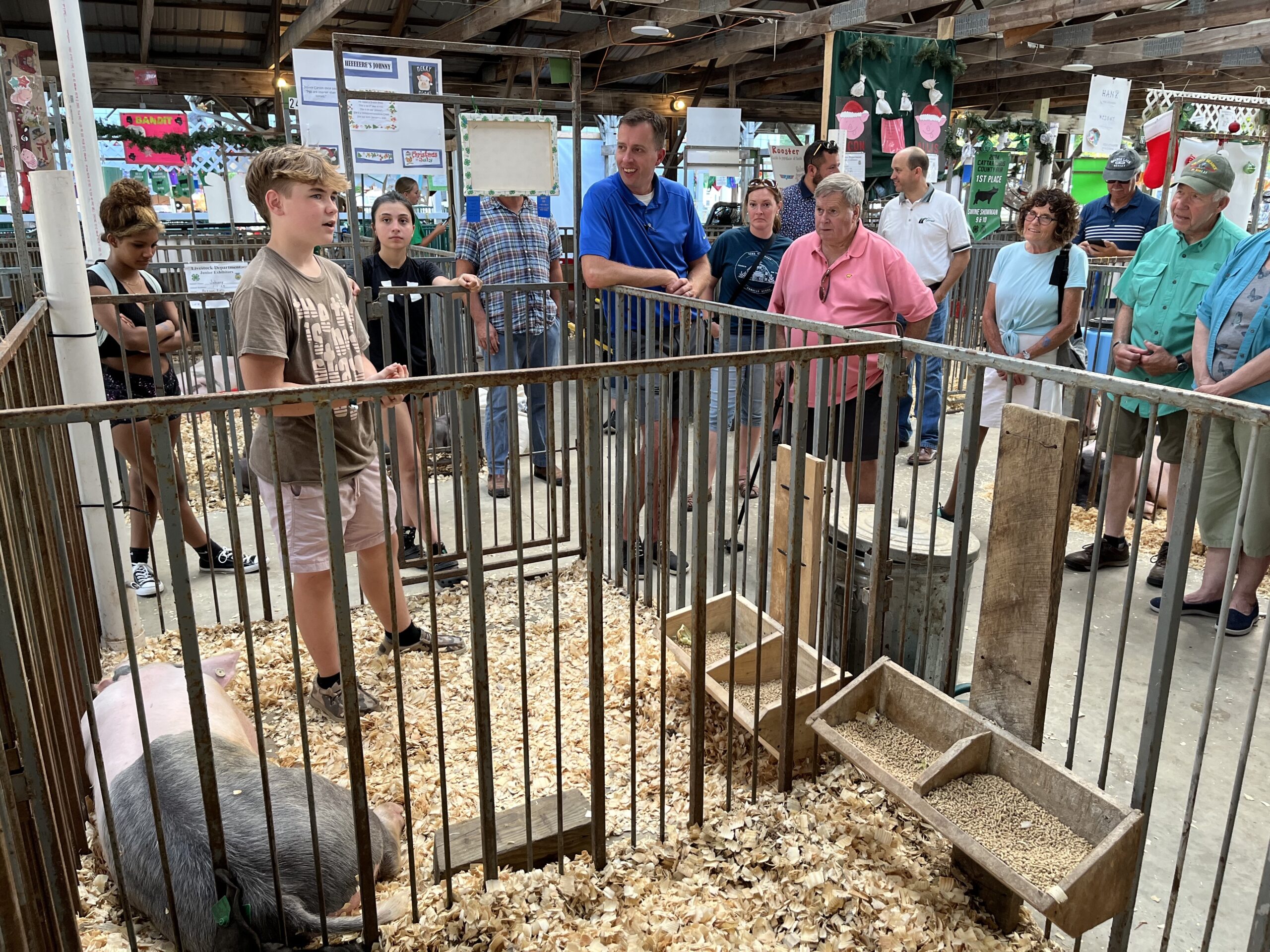 (Rick Miller/Olean Star) Logan Goddard, 14, a 4-H member from Irving, speaks at the Cattaraugus County Fair Wednesday with county legislators and members of the Cornell Cooperative Extension board during a tour of the fairgrounds. His hog Fabio Sparklmane, lies at his feet.