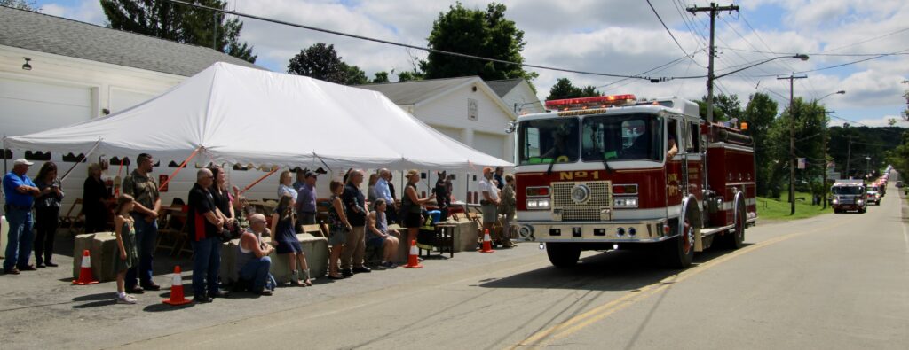 (Rick Miller/Olean Star)  A fire engine from the Conewango Fire Department passes by the East Otto Fire Hall Wednesday after a funeral in Little Valley for Tim Lexer, a longtime firefighter and former chief who also worked as a 911 dispatcher