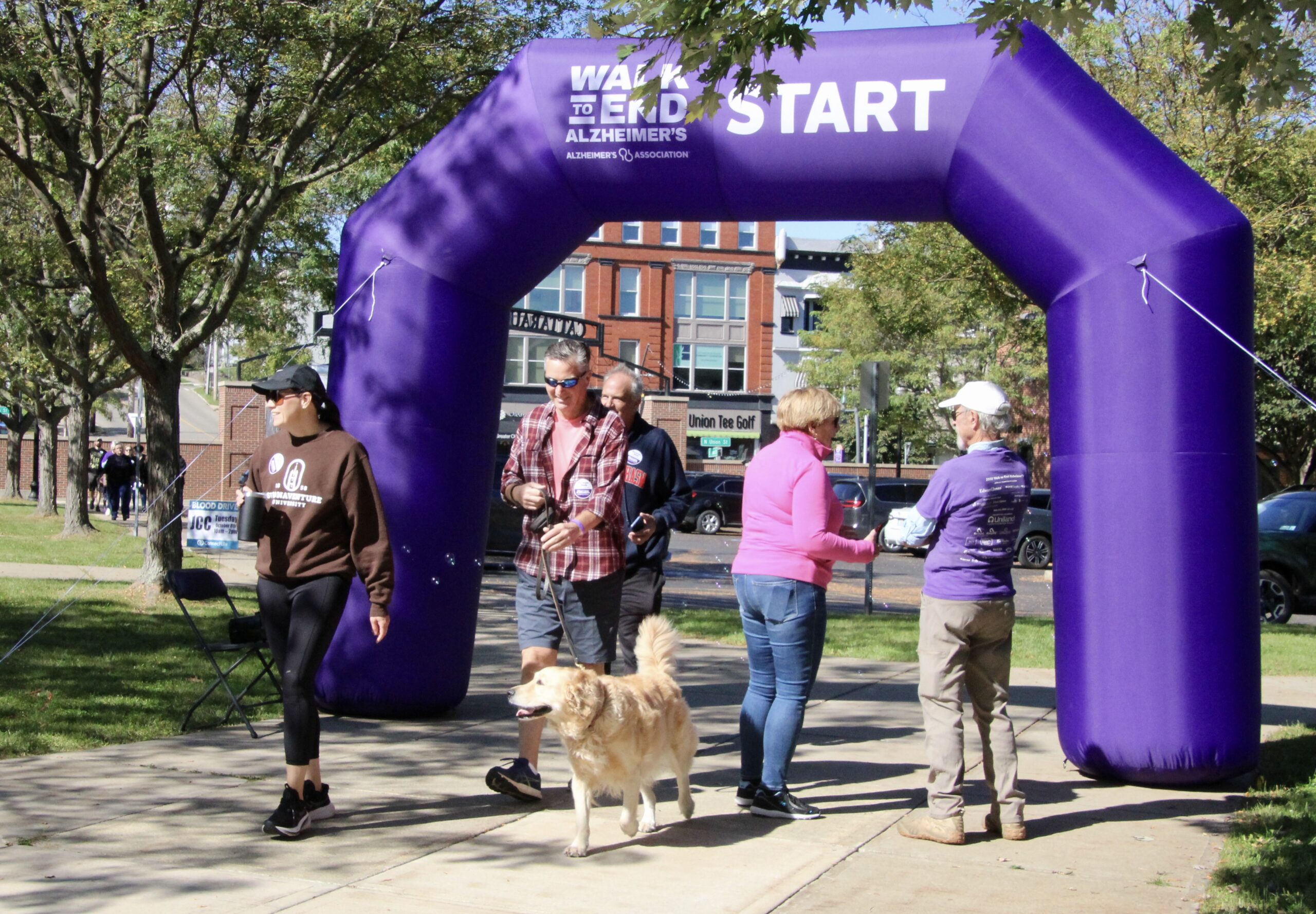 (Rick Miller/Olean Star) Misty Schuman, Brian Hall and Mike Conroy of Allegany cross the Walk to End Alzheimer's with golden retriever Moose Saturday morning at Jamestown Community College's Cattaraugus County Campus in OIean.