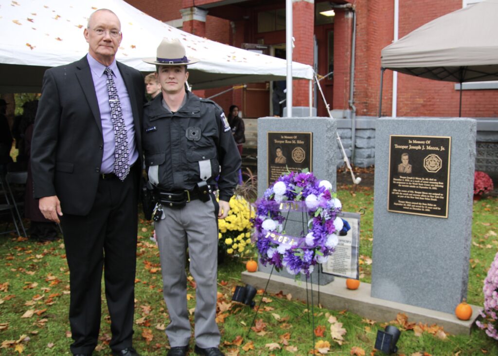 (Rick MIller/Olean Star)  State Trooper Robert Sawicki Jr. (left) and his father, Inv. Robert Sawicki Sr., stand next to the memorials for fallen Troopers Ross M. Riley and Joseph J. Mecca Jr. following Sunday's dedication ceremony outside the Olean State Police Substation.