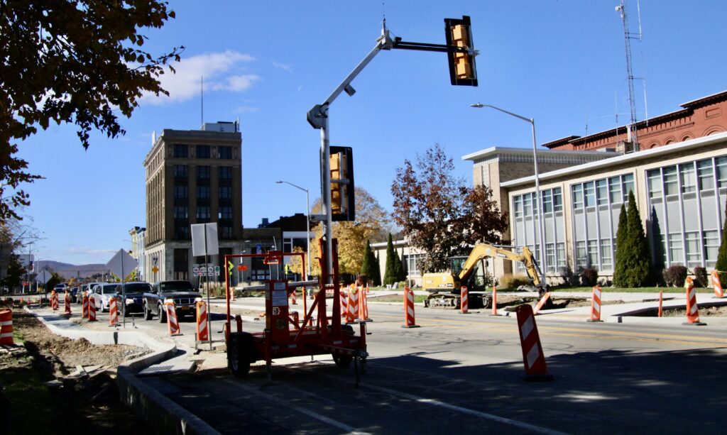 (Rick Miller/Olean Star) Eric Toegel of Millennium Construction holds onto the bucket of an excavator to smooth concrete at the mini-roundabout at East State and Barry streets Thursday.