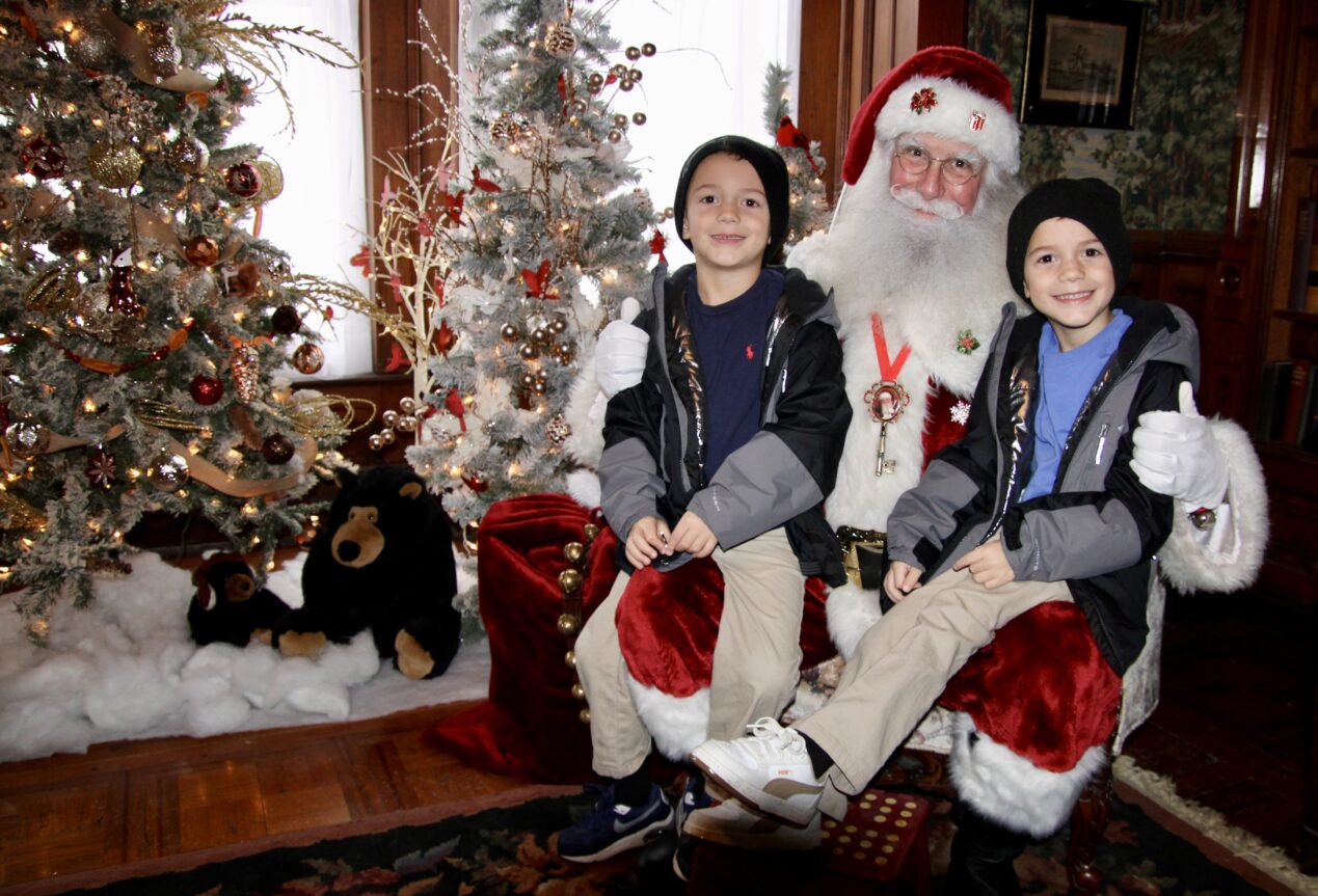 (Rick Miller/Olean Star) Twins Khalib Burney (left) and Khalil, sons of Malik Burney of Olean, sit on Santa’s lap Saturday at the Victorian Christmas celebration at the Fannie Bartlett House.
