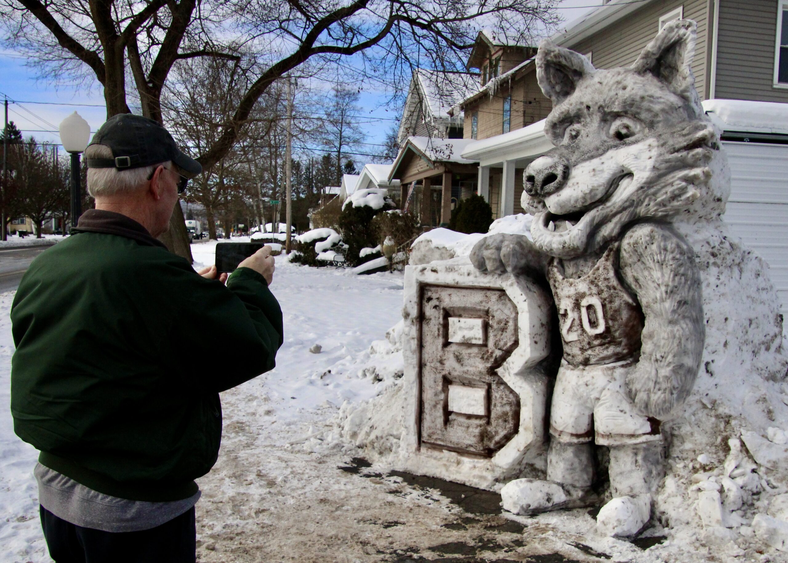(Rick Miller/Olean Star) Kevin McCarthy of Olean takes a photo Thursday of the 9-foot Bona Wolf Eric Jones sculpted out of snow outside Worth W. Smith Hardware on West State Street.