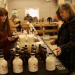 (Rick Miller/Olean Star) Kellie Bernd (left) of Brookside Maple in Centerville, waits on a shopper Saturday at the Olean Farmers Market that will set up at Canticle Farm Market on Old State Road in Allegany every other Saturday from 11 a.m. to 2 p.m. for the next two months.