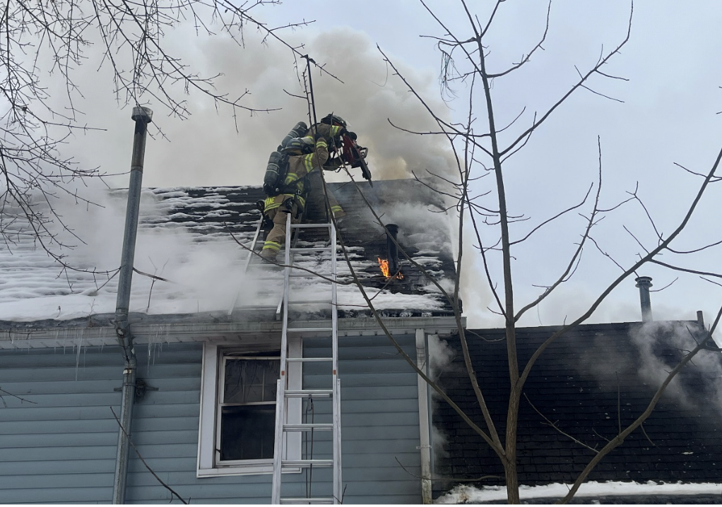 (Olean Fire Department photo) Olean firefighters cut a hole in the roof at a two-story home at 116 S. 16th St., where fire broke out Monday afternoon. A fireman was taken to the hospital for a medical evaluation. A dog died in the fire.