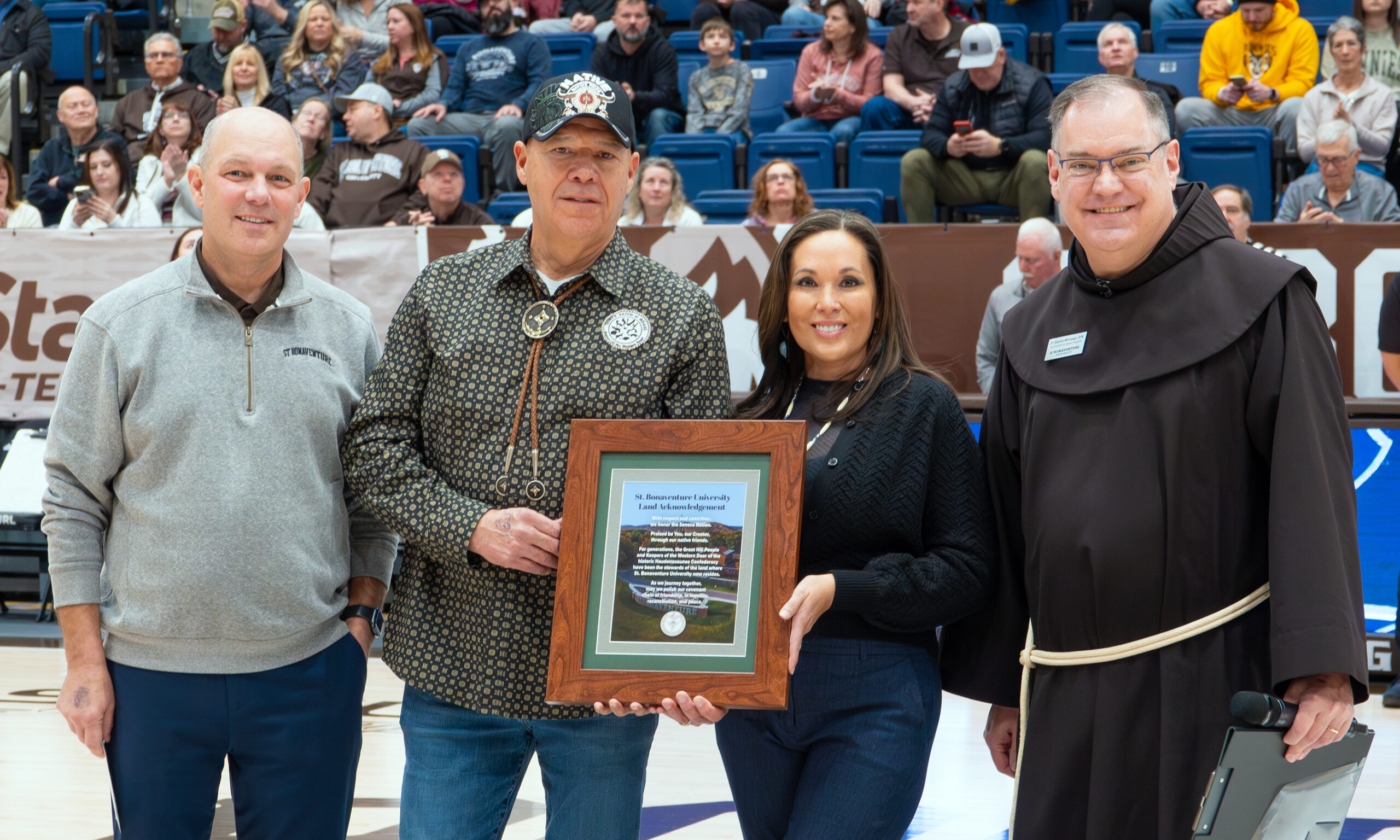 (St. Bonaventure photo) Captions: President Jeff Gingerich (left) presented Seneca President J. Conrad Seneca and First Lady Nicole Seneca with a framed print of the statement and a $1,000 donation to the Faithkeepers School. Fr. Stephen Mimnaugh, O.F.M., (right) read the Land Acknowledgment.